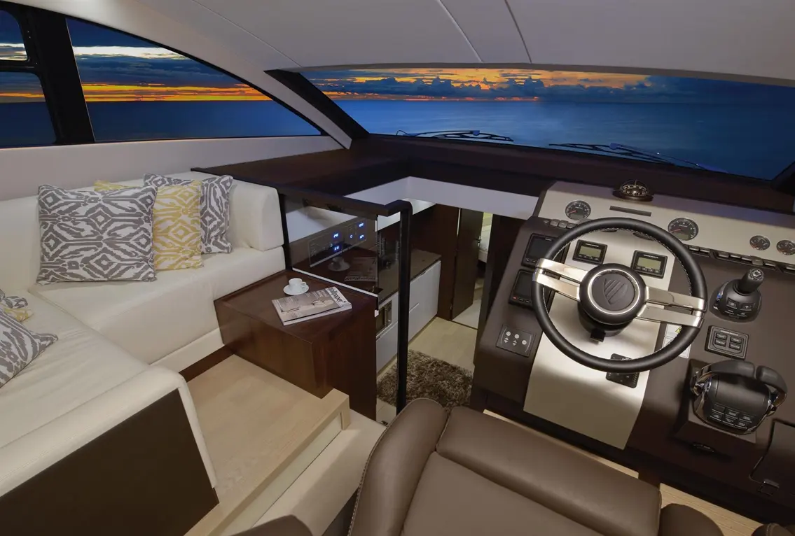 Luxurious yacht interior featuring a sleek steering wheel, comfortable seating, and a stunning sunset view through large windows.